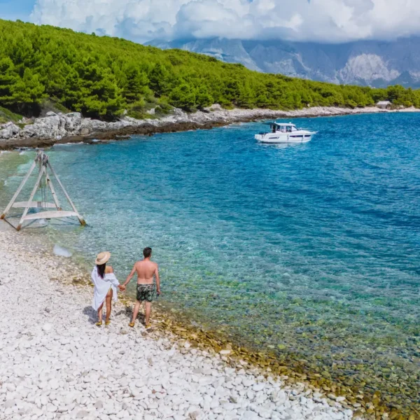 Couple enjoying a hidden Adriatic bay with a boat anchored nearby