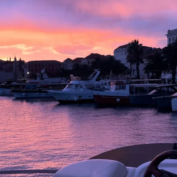 Boats in Split harbor at sunset with colorful sky during a private boat tour experience