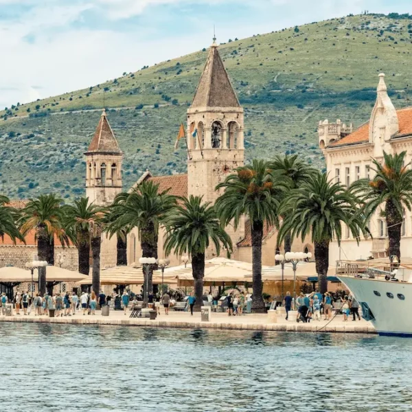 Trogir waterfront promenade with palm trees, historic buildings and boats along the Adriatic coast