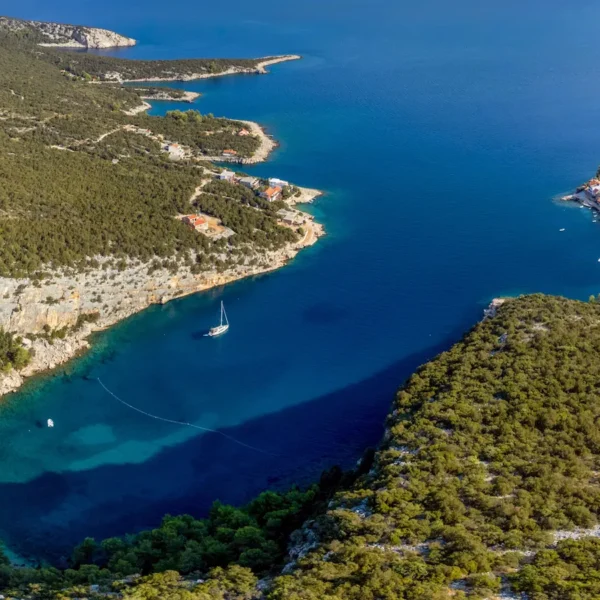 Aerial view of a hidden Adriatic bay with a boat anchored in crystal clear water along the Croatian coastline